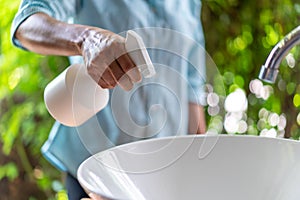 Close up to Asian female hand. she holds the white sprayer / foggy for wash and clean sink at outdoor garden to protect