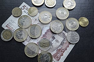 Close up to a colombian money paper and colombian coins over black background.