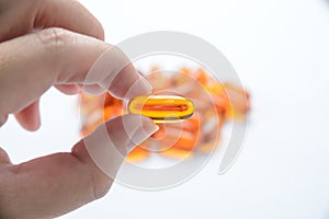 Close up to fish oil capsule in fingers