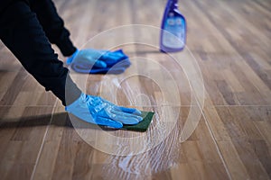 Close up to hand is cleaning a stain on a floor tile with disinfectant