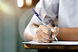 Close up to hand of student  holding pen and taking exam in classroom with stress for education test