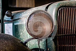 Close up to the lights of an old dirty, rusty, grungy and full of spider webs truck on a sunny day