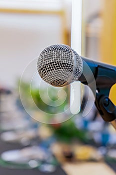 Close up to microphone beside the podium with blur long black table dinner time in tungsten warm light