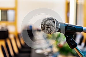 Close up to microphone beside the podium with blur long black table dinner time in tungsten warm light