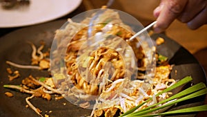 Close up to a plate of thai traditional food, Shrimp Pad Thai, dry noodle street food in Thai food style while stiring in plate