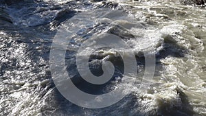 Close-up to the river swollen after heavy rainfall and flood water crashing through valley