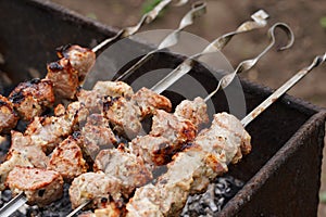 Close up of toasted shashlik on skewers. Succulent barbecue roasting on chargrill. Concept of picnic outdoor