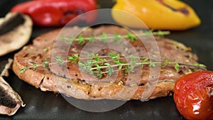 Close-up, toasty gammon steak cooking on the grill with thyme and vegetables, 4K