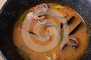 Close up Tom Yum soup with seafood top view. Octopuses and shells in soup.