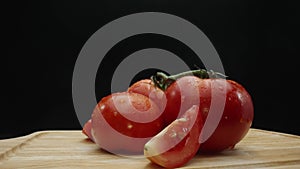 Close up of tomato sliced on cutting board with black background. Comestible.