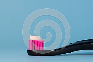 Close up toothbrush neon pink color with toothpaste on blue background. Dentists day concept. Toothbrush day. Copy space