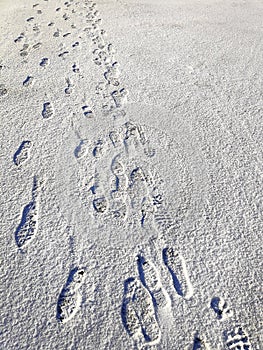 Close up top above view of people footprints on white icy snow concrete pavement surface background. Winter walking on
