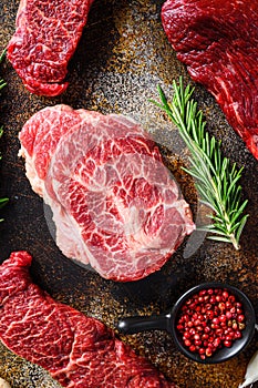 Close up top blade steak cutwith set of different alternative types of raw beef steaks on a rustic metall background top view
