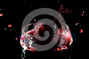Close-up of the top of a clear glass goblet filled with wine with splashes of water. Splash Effect