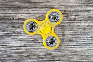 Close up top high angle above view photo of popular yellow fidget spinner, stress relieving toy against grey wooden background iso photo