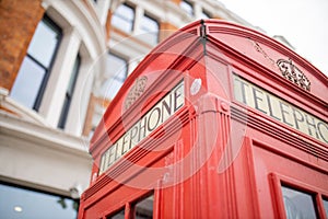 Close up of the top of a London telephone booth and a brick building behind it