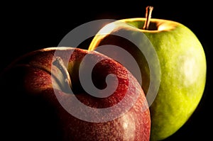 Red apple with a green apple in low-key on black