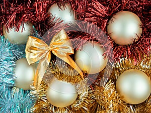 Close up top view of 7 matte yellow-beige Christmas balls,shiny metal celebration tinsel,garlands in red,gold,bluish