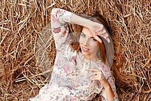 Close-up top view of a beautiful young blonde girl on a background of haystacks