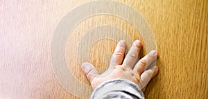 Close up top view of child`s hand isolated on wooden background