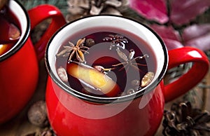 Close up top view of colorful cups of traditional Christmas drink mulled red spiced wine with cinnamon stick, apples and citrus on