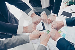 Close up top view cropped photo of experts in elegant classic outfit putting their fists together in a circle standing in work pl