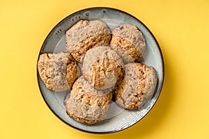 Close up top view on crunchy oatmeal chip cookies fresh baked biscuits with chocolate and cocoa in a plate on the yellow modern