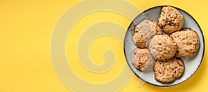 Close up top view on crunchy oatmeal chip cookies fresh baked biscuits with chocolate and cocoa in a plate on the yellow modern