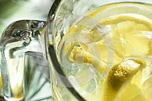 Close up and top view of frozen glass pitcher with lemonade with ice and lemon pieces floating in water. Refreshing summer drink
