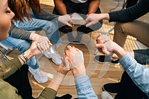 Close-up top view of group diverse multiethnic people holding hands together during the psychological therapy.