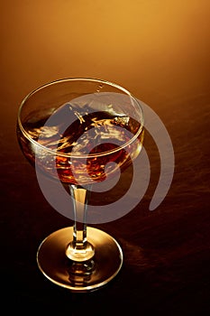 Close up top view of high glass of whiskey, rum, brandy or gin over warm gradient background.