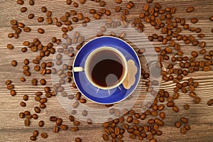 Close-up and top view of hot black coffee in blue coffee cup and roasted Thai coffee beans on wooden background