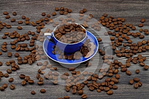 Close-up and top view of hot black coffee in blue coffee cup and roasted Thai coffee beans on wooden background