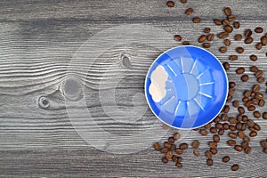 Close-up and top view of hot black coffee in blue coffee cup and roasted Thai coffee beans on wooden background