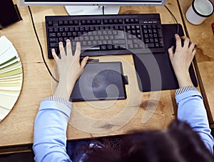 Close-up top view image of female hands, graphic designer, retoucher working, using graphic tablet and keyboard, editing