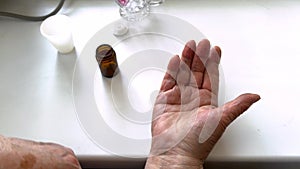 Close up top view of pensioner pours pills on her hand. Older woman taking daily dose of medications