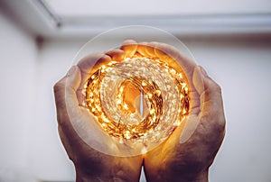 Close up top view of person holding roll of wire micro LED string lights in hands.