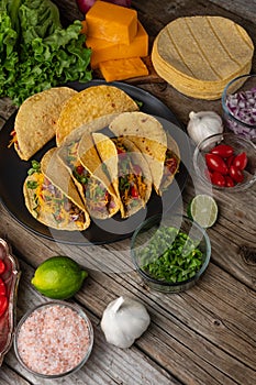 Close-up top view of plate with mexican tacos on rustic wooden table with ingredients for cooking background. Concept of