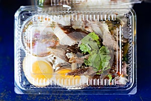 Close-up top view of pork leg rice in a clear plastic box