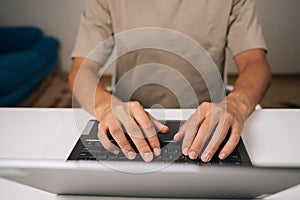 Close-up top view of programmer male hands typing code on laptop keyboard, showcasing process of software development