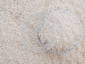 Close up top view rice in a white bowl and scattered near on wooden table with copy space for text and design