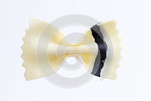 Close up top view shot of an isolated white and black colored raw Italian farfalle bow pasta on a white background