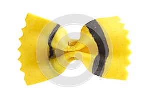 Close up top view shot of an isolated yellow and black colored raw Italian farfalle bow pasta on a white background