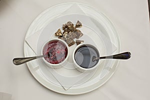 Close up top view shot of two white cups with soy sauce and red vinegar mignonette marinade with shallots inside, on a white plate