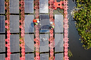 Close up and top view of two technician workers set up or install solar cell panel over the water reservoir as solar farm factory