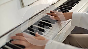 Close-up top view of unrecognizable young woman musician performer playing on classical piano at home enjoying virtuoso