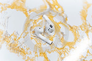 Close-up top view of wireless earphones on background of white yellow marble table.