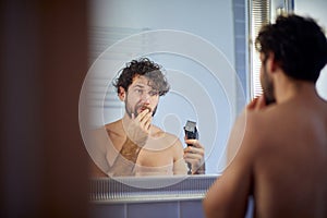 Close up of a topless man shaving with shaver