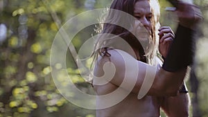 Close-up of a tough guy with long hair and a knife in his hands. He strikes at an imaginary enemy.