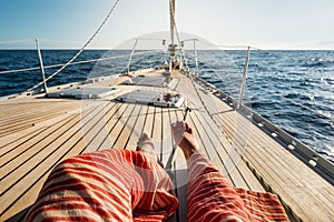 Close up of tourist woman caucasian feet lay down and relaxing enjoying a sail boat trip with ocean around and horizon in